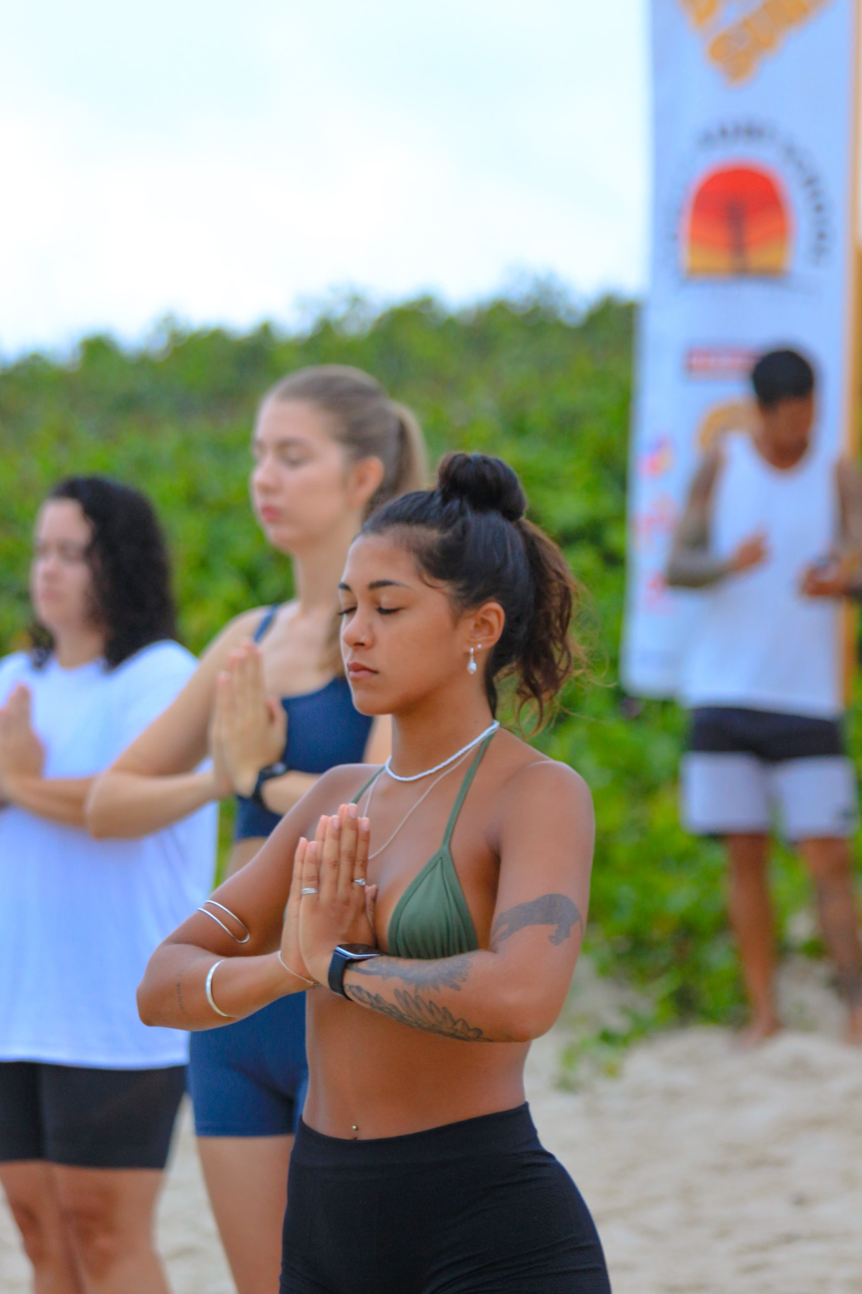 Alunas em momento de meditação e respiração na areia antes da aula de surf